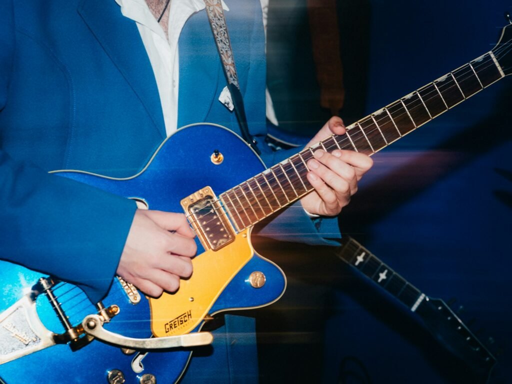 Person plays a blue electric guitar with passion.